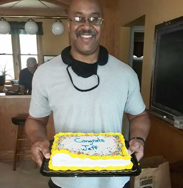 Jeff holding a congrats cake celebrating his release from parole